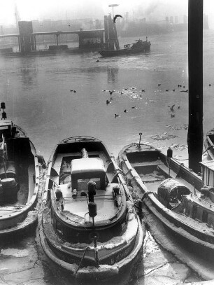 Hamburg. Kaianlagen (Kajen) im vereisten Binnenhafen. Kleine Motorschiffe liegen im teilweise zugefrorenen Hafenbecken vor Anker