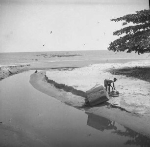 Mann am Strand : Ein Mann steht an einem Wasserlauf zum Ozean.