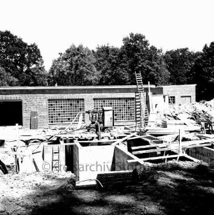 Abwasser: Klärwerk: Wöhrendamm: 3. Bauabschnitt: Baugrube mit Schmutzwassereinläufen: darauf Wasserpumpe und Baumaterial: hinten Maschinen- und Betriebsgebäude im Rohbau: im Hintergrund Bäume