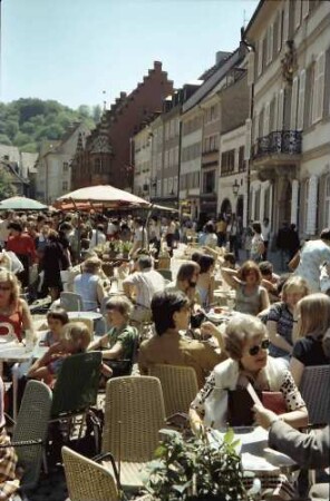 Freiburg: Roter Schirm, Münsterplatz mit Tischen, Hintergrund Kaufhaus