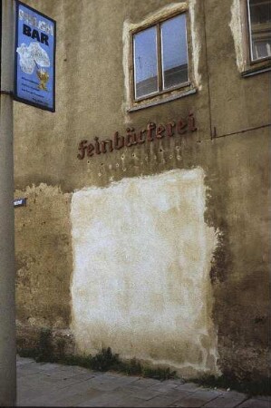 DDR. Teilansicht der Fassade eines maroden Wohnhauses mit Ladeneinbau für eine Feinbäckerei. Ansicht mit vermauertem Ladenteil