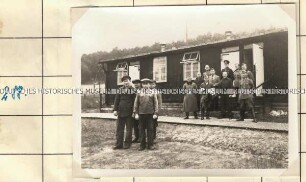 Angehörige der Ordnungspolizei und Zivilisten vor eine Holzbaracke