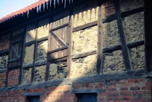 Detail einer Scheune: Fachwerk im Obergeschoss, Luken mit Holzläden