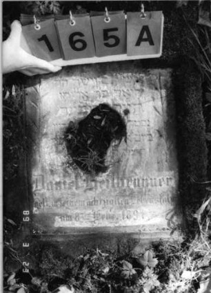 Grabstein 165 (Index: 99792282) Material: Sandstein, weiße Marmorplatte Zustand: beschädigt und verwittert mit Textverlust, Stele liegend Maße HxBxT: 112x56x13 cm Beschreibung: Stele, Schriftplatte mit eingezogener Rundbogenabschluß: Grabstein 165A