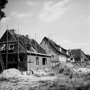 Gartenstraße: Neubaugebiet mit Einfamilienhäusern: vorn links und hinten rechts Rohbauten mit Gerüsten: dazwischen Häuser nach Fertigstellung: vorn Sandhaufen und Baumaterial