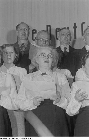 Der Chor des VEB Eilenburger Celluloid-Werk mit dem Liederbuch "Reicht Euch die Hände" beim Bezirksausscheid der Volkskunstgruppen 1954