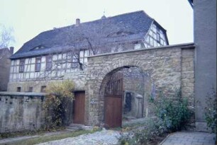 Pfarrhaus, steinerner Torbogen und gepflasterte Zufahrt zum Pfarrhof