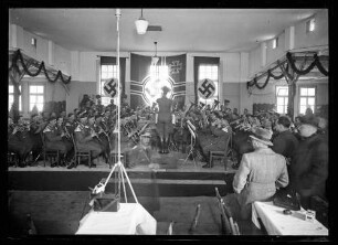 Musikkapelle in Wehrmachtsuniform spielend, im Hintergrund Reichskriegsflagge