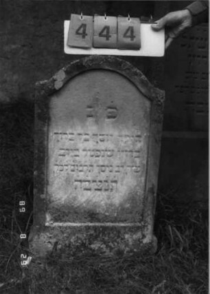 Grabstein 444 (Index: 100107977) Material: gelber Sandstein Zustand: verwittert Maße HxBxT: 81x47x12 cm Beschreibung: Stele, Konvexbogenabschluß, Schriftfeld eingetieft, Sockel: Grabstein 444