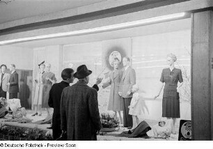 Besucher vor einem Schaufenster mit Damen- und Herren-Bekleidung