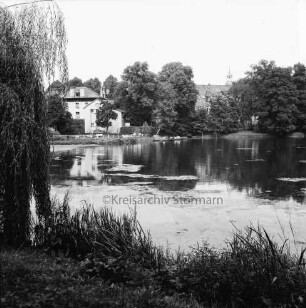 Mühlenteich: Blick von Süden Am Mühlenteich auf gegenüberliegendes Ufer: hinten links zwischen Bäumen Elektriziätswerk Reinbek-Wentorf GmbH [später: e-werk Sachsenwald]): hinten rechts Schloss Reinbek hinter Bäumen: links Baum