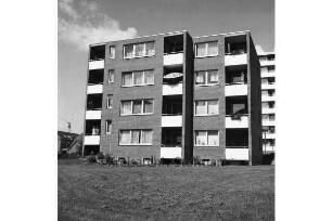 Wohnblock der Gemeinnützigen Wohnstättengenossenschaft eG Bad Oldesloe: dahinter rechts Hochhaus, links Reihenhaus und Baukran: davor Grünanlage