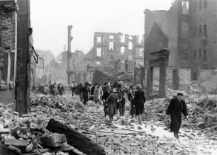 Hamburg. Bewohner Hamburgs laufen durch die zerstörte Innenstadt. Rechts und links der mit Trümmern übersäten Straße stehen Ruinen