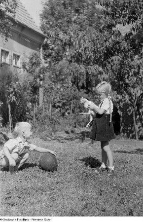 Zwei Kinder im gemeinsamen Spiel mit einem Ball und einem Huhn