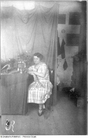 Die Bildhauerin Etha Richter, neben einem Blumenstrauß sitzend (vielleicht in ihrem Atelier)