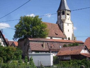 Ansicht von Süden mit Kirche (Chorturm mit Schlitzschartren) über Kirchhofmauer in erhöhter Lage im Ort