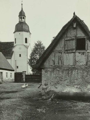 Zabeltitz. Strohgedecktes Fachwerkhaus und Turm der St.-Georgen-Kirche