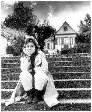 Fotomontage: Rauchende junge Frau sitzt auf der Treppe vor einem Haus (Altersgruppe 18-21)