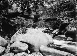 Granitblöcke in einem Flusslauf : Granitblöcke wahrscheinlich im Flusslauf des Rio Huato bei Camata. Im Hintergrund einige Männer auf einer Holzbrücke.