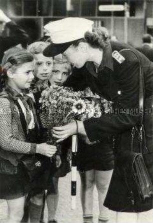 Kinder überreichen einer Volkspolizistin Blumen