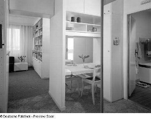 Musterwohnung (1972; Deutsche Bauakademie). Blick vom Bad über den in die Anbaumöbel integrierten Eßplatz zum Wohnzimmer (Fotocollage ?)