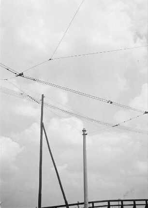 Hölzerner Telegrafenmast mit zwei Stützisolatoren und Leitungen, Stahlbeton-Abspannmast für Einfachfahrleitung der Straßenbahn und weitere Freileitungen, zu denen keine Masten sichtbar sind