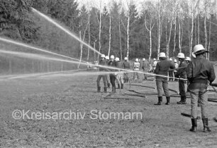 Großübung: Festplatz Klein Wesenberg: Feuerwehrmänner mit Feuerwehrschläuchen beim Löschen: im Hintergrund Bäume