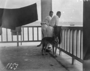 Männer auf einer Terrasse : Zwei Männer und ein Schäferhund auf einer Terrasse