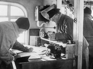 Eintragung von Positionen : Lieutnant Edward Smith (1889-1961) und Fleming im Navigationsraum des Luftschiffs beim Eintragen von Positionen.
