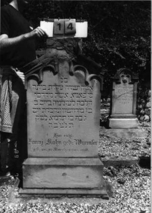 Grabstein 14 (Index: 99796569) Material: Sandstein Zustand: Abschluß beschädigt Maße HxBxT: 122x63x19 cm Beschreibung: Stele, Sockel, giebelart. Abschl. m. Verdachung, rechteck. erhöht Symbolik: gestelztes Rundbogenfries: Grabstein 14