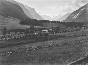 Ernte im Tal : Heuhaufen an einem Feld mit Gehöft in einem Tal. Im Hintergrund Berge