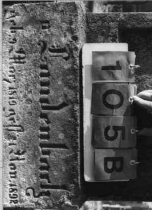 Grabstein 105 (Index: 100116415) Material: Sandstein Zustand: rechter oberer Teil der Stele abgebrochen mit Textverlust Maße HxBxT: 165x56x25 cm Beschreibung: aufgesockelte Stele mit Rundbogenabschluß, eingetieftem Schriftfeld und Schriftfeld am Sockel: Grabstein 105B