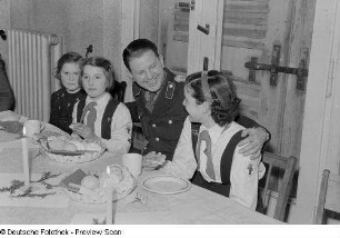 Pioniere mit einem Polizisten am Tisch sitzend