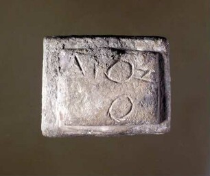 Zweistufiges, rechteckiges Gewicht (attischer Standard, Viertelminenstück) mit griechischer Inschrift (ΔΙΟΣ und zusätzlichem Omikron unterhalb des Omikrons)