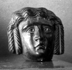 Jugendliche Maske mit etwas schmerzlichem Ausdruck und symmetrisch herabhängenden Locken