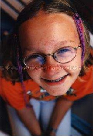 Mädchen mit Brille, Zahnspange und bunten Zöpfen (Altersgruppe bis 14)