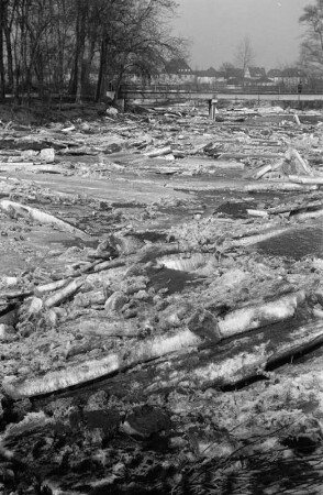 Eisschollen auf der Weißen Elster : Gestapelte Eisschollen auf der Weißen Elster. Im Hintergrund eine Stadt mit Brücke