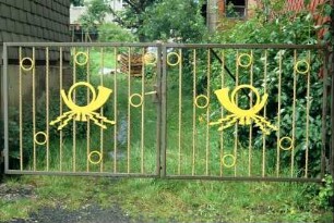 Metallgittertor mit zwei gelben Posthörnen