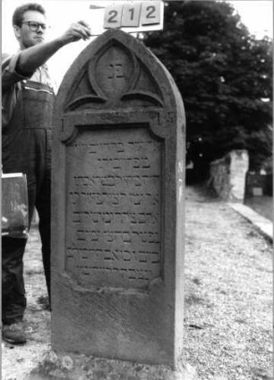 Grabstein 212 (Index: 99797671) Material: Sandstein, rot Zustand: gut Maße HxBxT: 153x53x16 cm Beschreibung: Stele, Spitzbogenabschluß Symbolik: Maßwerk: Grabstein 212