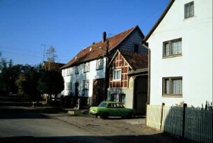 Dorfstraße, Gehöfte in unterschiedlicher Form; vorn Wohnhaus mit Vorgarten
