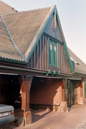 Fritz-Berodt-Straße 7-9: Hofanlage: Haus Nr. 7 [Haus am Teich]: Traufseite zum Hof, Teilansicht: ehemalige Remise, darüber Frontispiz mit Verbretterung, Luke, oben Giebelzier, rechts moderner Eingangsbereich mit Verglasung, Tür