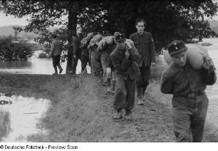Helfer beim Tragen von Sandsäcken auf einem Damm
