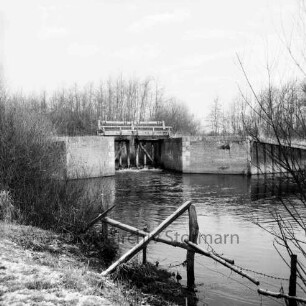 Ehlersberg: Alster: Tangstedter Schleuse (auch: Heidkruger oder Ehlersberger Schleuse): vorn Zaun an Uferböschung: links Sträucher: hinten Bäume: Winter