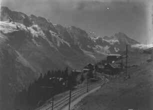 Mürren mit Mittagshorn, Grosshorn, Breithorn : Mürren mit Mittagshorn, Grosshorn, Breithorn in den Berner Alpen. Im Vordergrund eine Eisenbahnstrecke und eine Siedlung