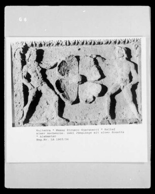 Relief einer Ascheurne: zwei Jünglinge mit einer Rosette