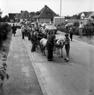 Dorffest der Dorfgemeinschaft Klein Wesenberg: Festumzug in Wohnstraße: im Vordergrund Anhänger mit Ponygespann: hinten Zuschauer, Pkws und Häuser