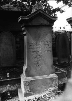 Grabstein 134 (Index: 100094247) Material: Sandstein Zustand: verwittert mit Textverlust Maße HxBxT: 187x64x29 cm Beschreibung: kon. Stele, profiliert. Sockel, eingezogener Giebel mit Mittelakroter Symbolik: Blätter im Akroter: Grabstein 134