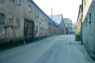 Dorfstraße mit dichter Bebauung durch Bauernhöfe, schlechter Fassadenzustand
