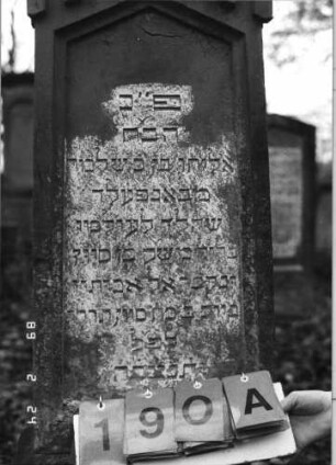 Grabstein 190 (Index: 99752053) Material: Sandstein Zustand: leicht verwittert Maße HxBxT: 148x38x27 cm Beschreibung: konische Stele, getreppt. Sockel, giebelart. Abschl. m. Verdach. , Schriftfeld eingetief Symbolik: gestelztes Rundbogenfries: Grabstein 190A
