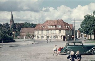 Sülzberg: vorn rechts parkender Pkw: davor und daneben vier Kinder: links Einmündung Kurparkallee: hinten rechts Einmündung Brunnenstraße: ehemaliges Hotel Holsteinisches Haus mit Anbau: hinten links Turm der Peter-Paul-Kirche